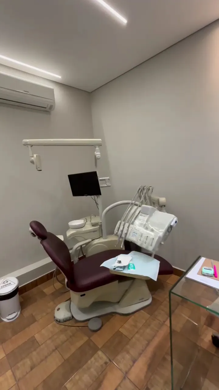 Consultório da clínica, com cadeira odontológica e monitor na parede