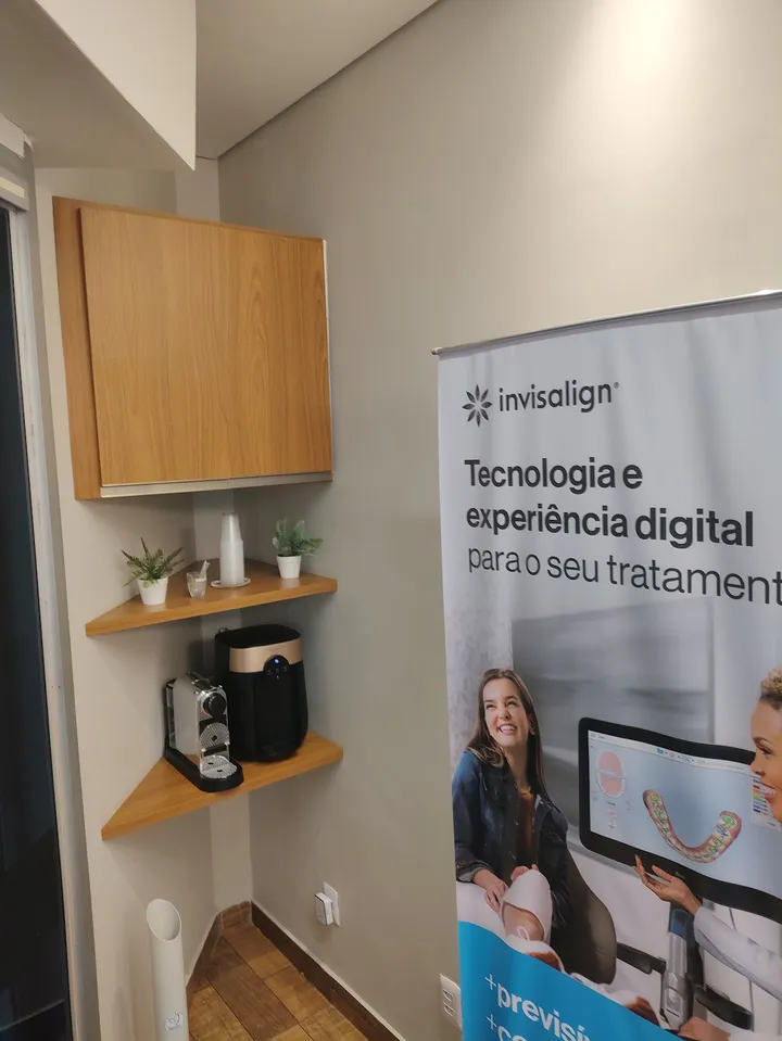 Canto da espera, com o banner do alinhador invisível e a máquina de café
